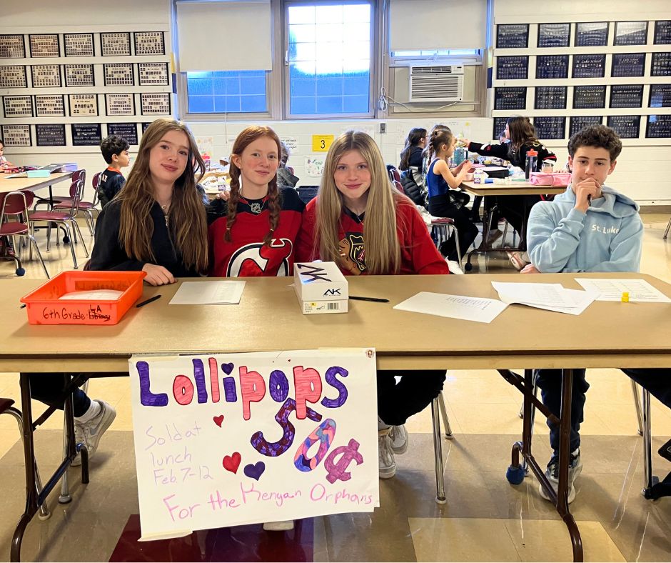 Smiling middle school students sitting at a table selling lollipops